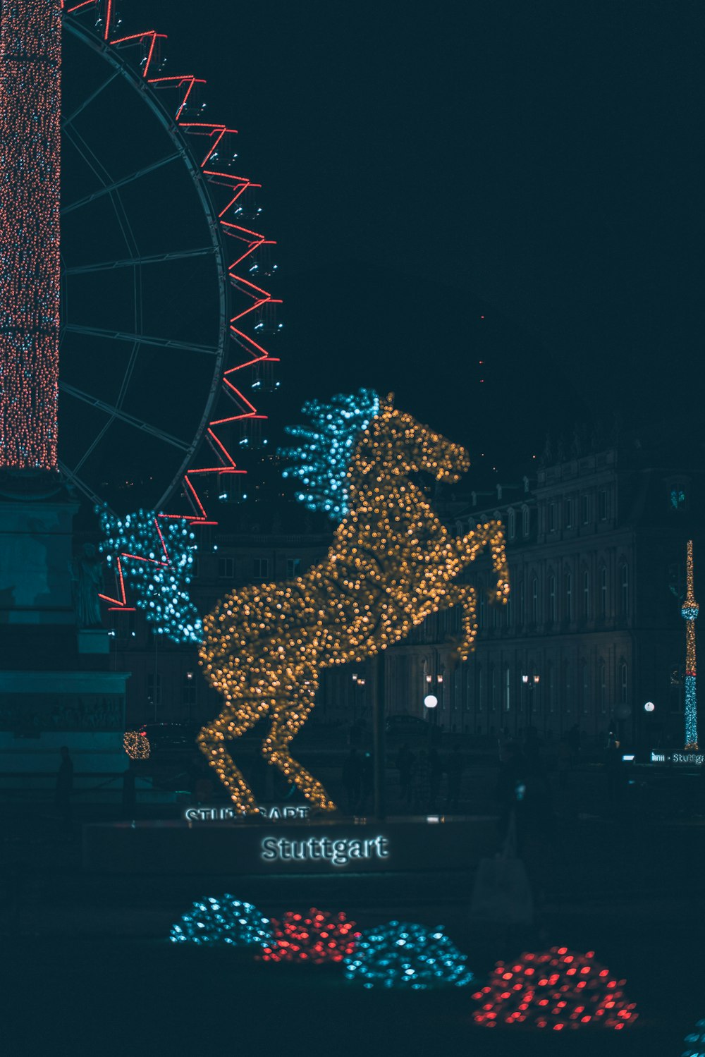 a statue of a horse with a ferris wheel in the background