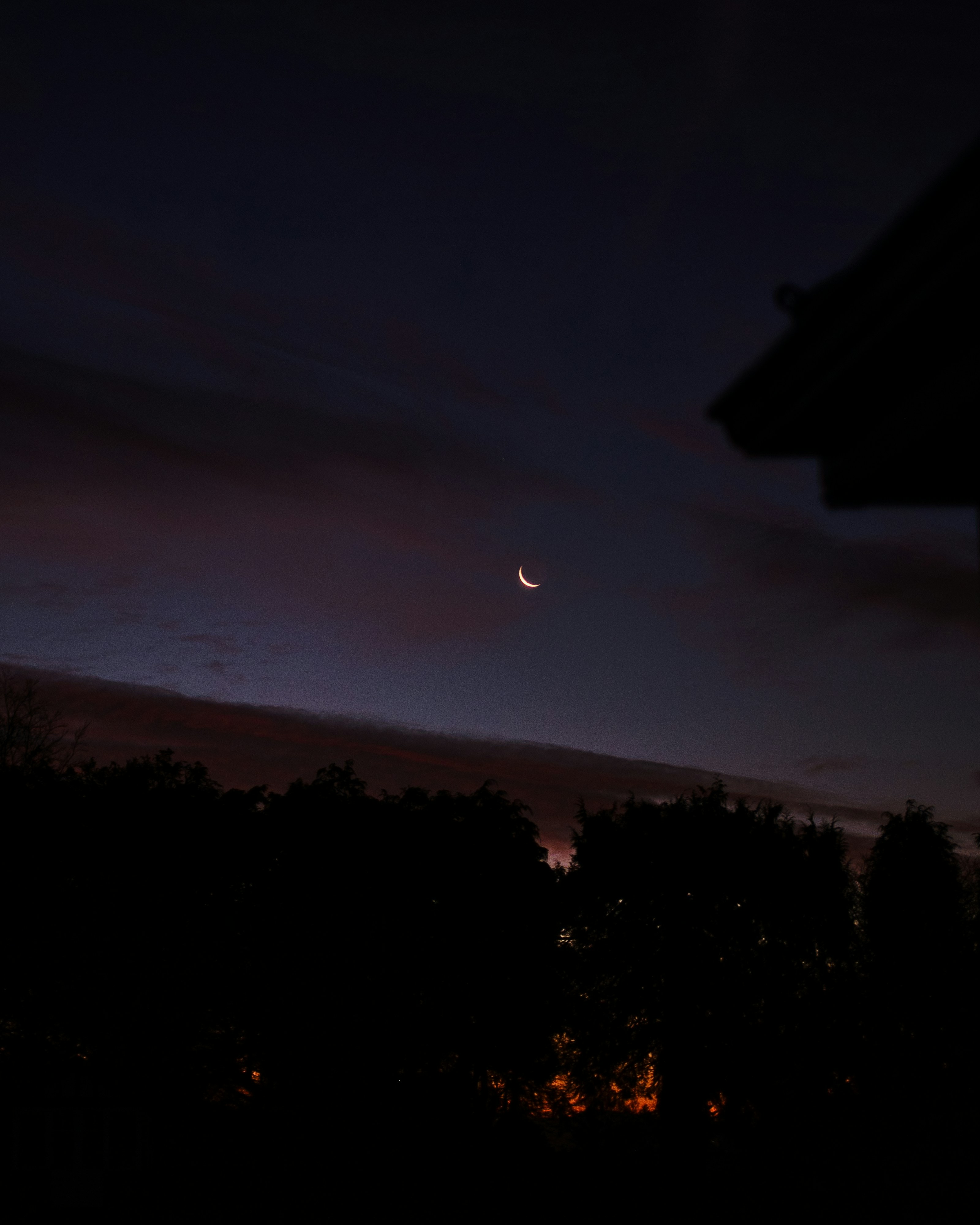 a view of the moon from a house at night