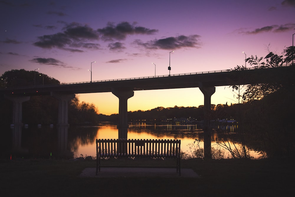 un banc assis sous un pont à côté d’un plan d’eau