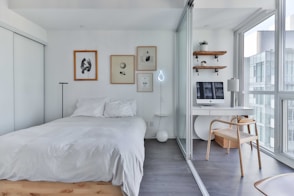a bedroom with a bed, desk, and a window
