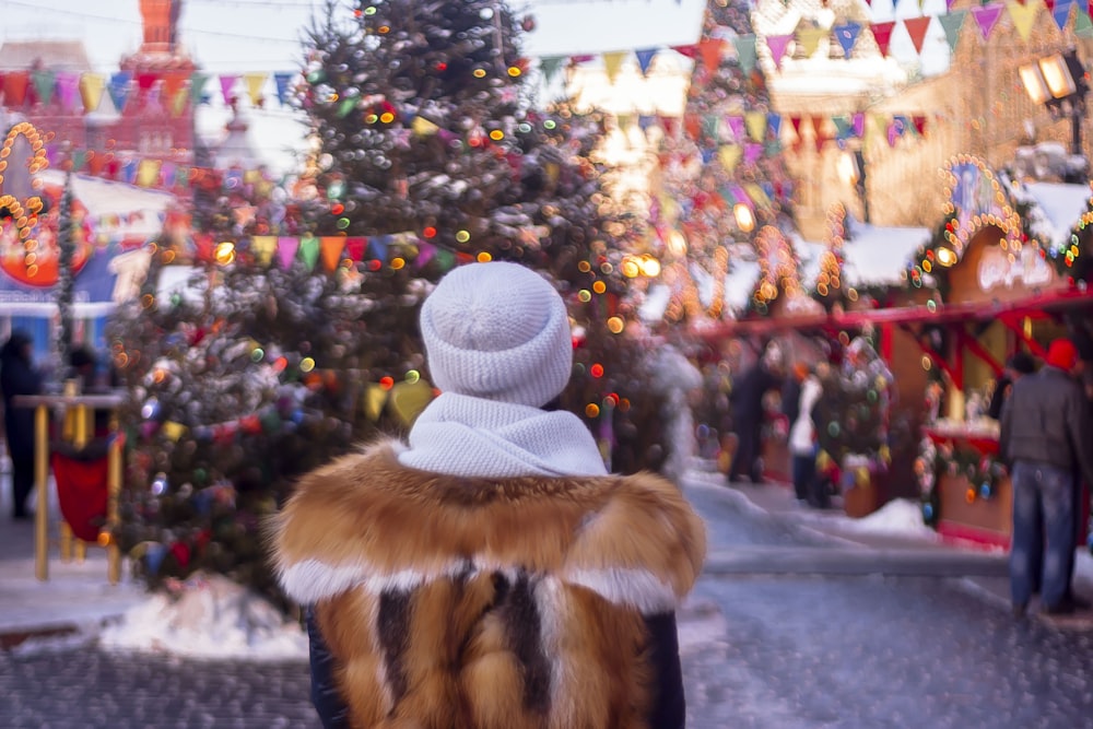 a woman standing in front of a christmas tree