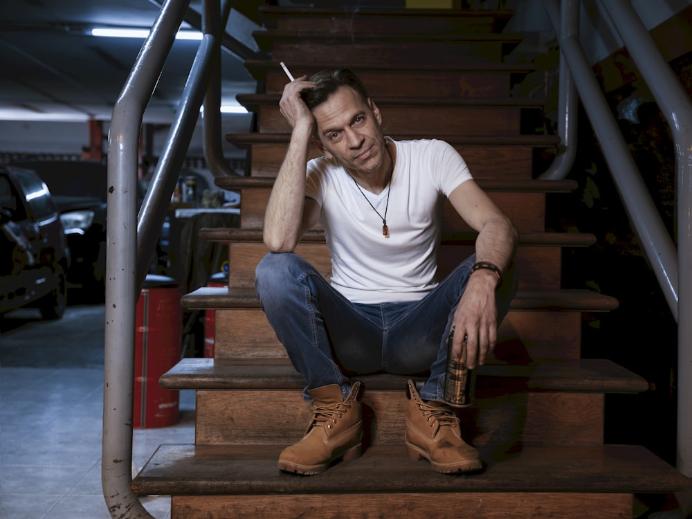 a man sitting on a stair case smoking a cigarette