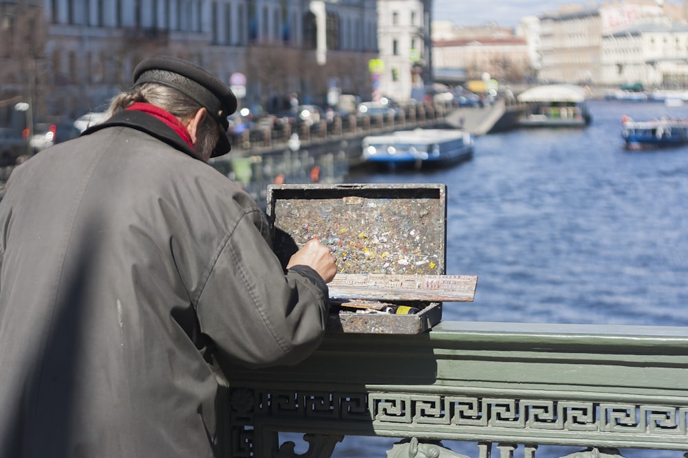 a man painting on a bridge over a river