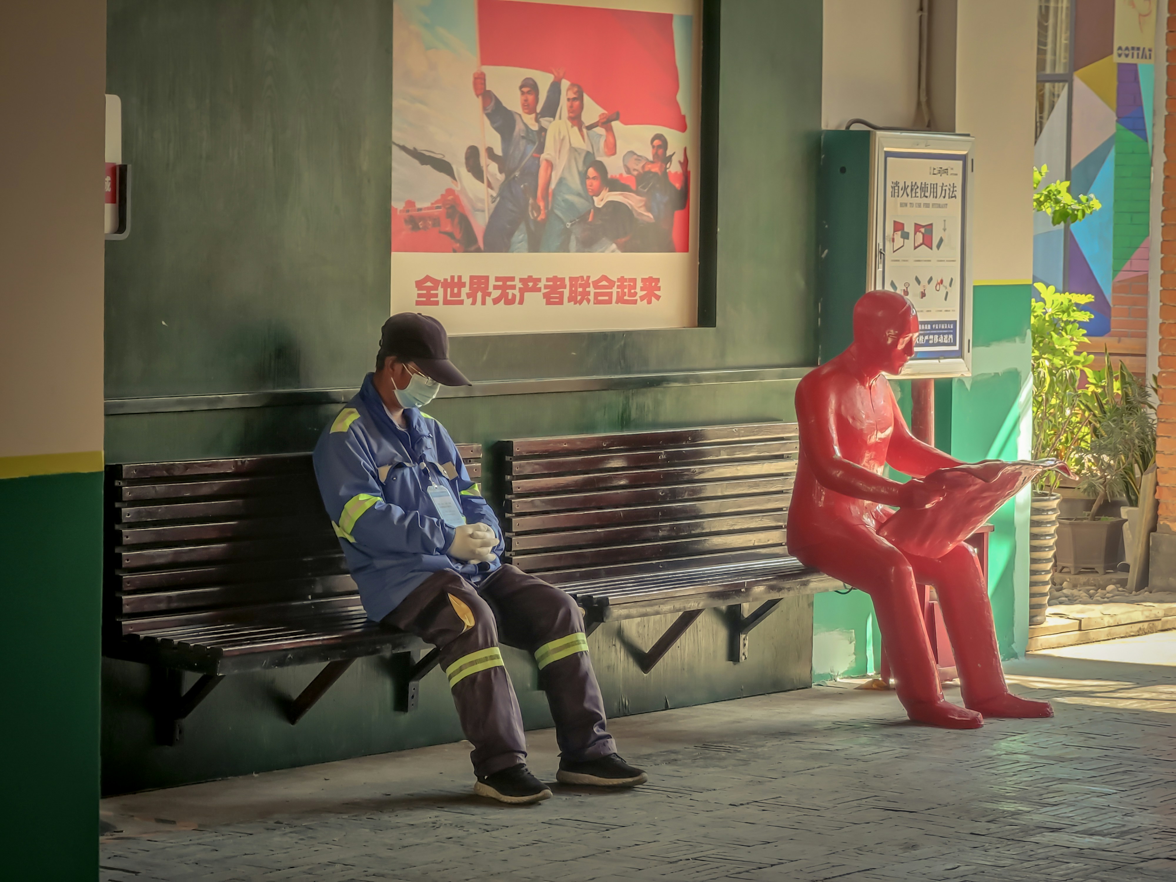 a man sitting on a bench next to a statue