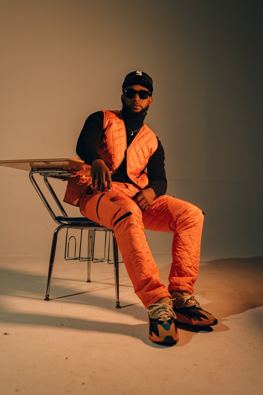 a man sitting on a chair wearing an orange vest