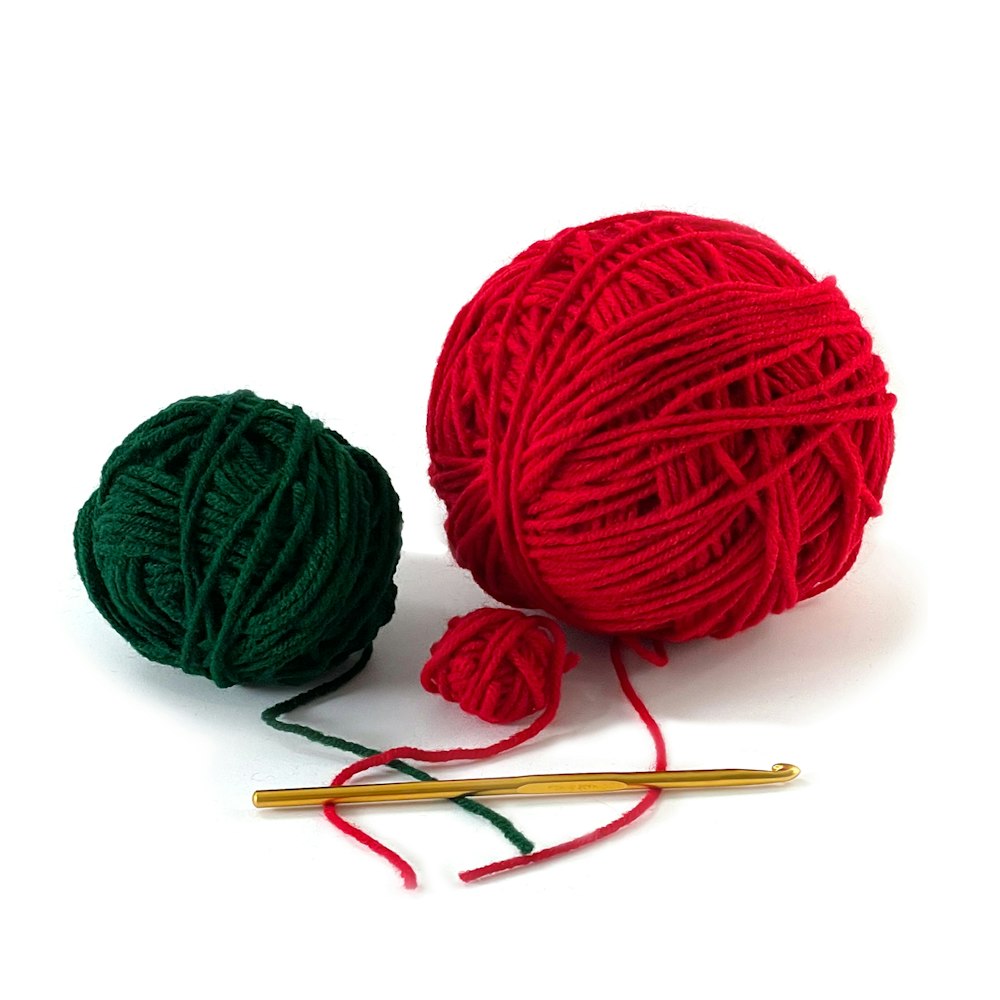 a ball of yarn next to a ball of knitting needles
