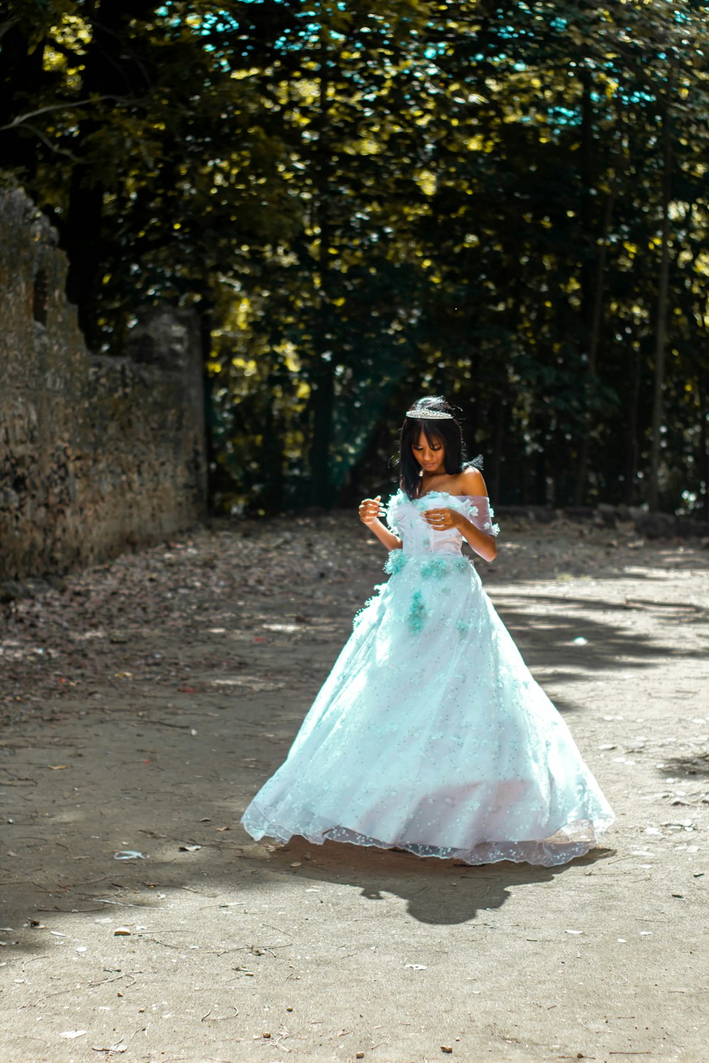 a woman in a white dress walking down a dirt road