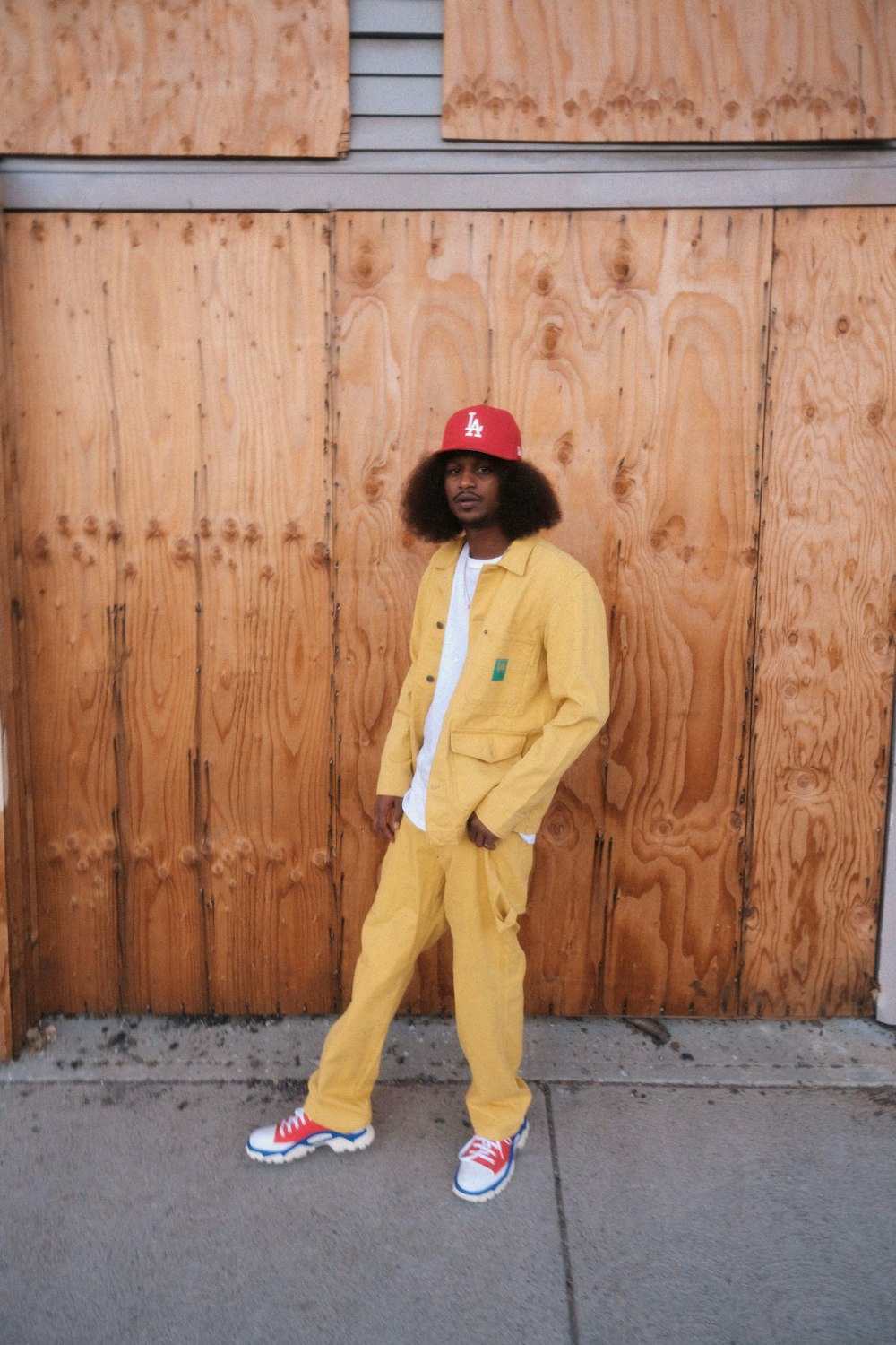 a man in a yellow outfit standing in front of a wooden wall