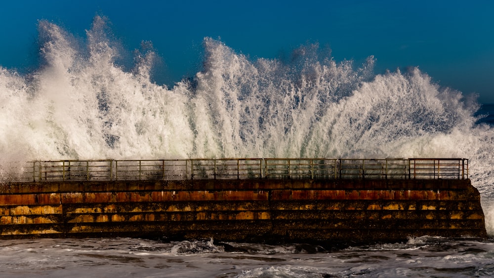 a large wave crashing over a pier in the ocean