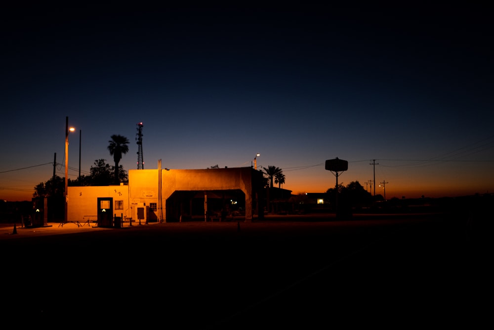 a gas station at night with palm trees in the background