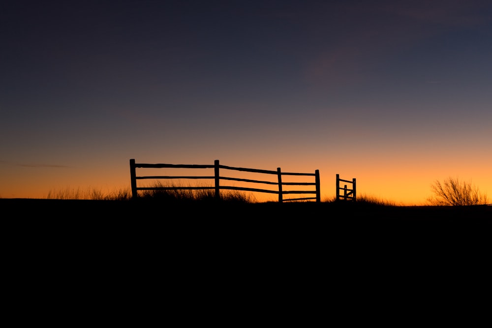 Ein Holzzaun auf einem Feld bei Sonnenuntergang