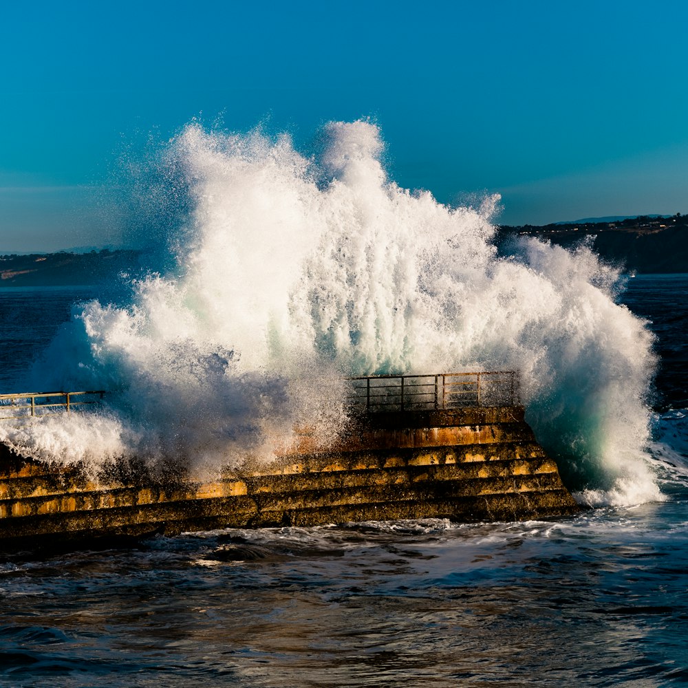 a large wave crashing over a pier on a sunny day