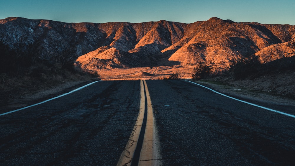 an empty road with mountains in the background