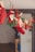 A string of Christmas-themed decorations hangs across the room, featuring red and green felt stockings and pouches, each adorned with numbers and simple patterns. Clothespins are used to attach the decorations to the ribbon, which is strung along a wall or through a doorway. The scene evokes a festive and cozy atmosphere.