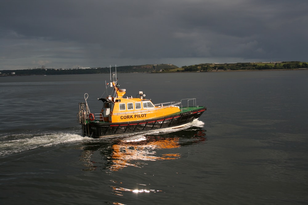 a yellow and black boat traveling across a body of water