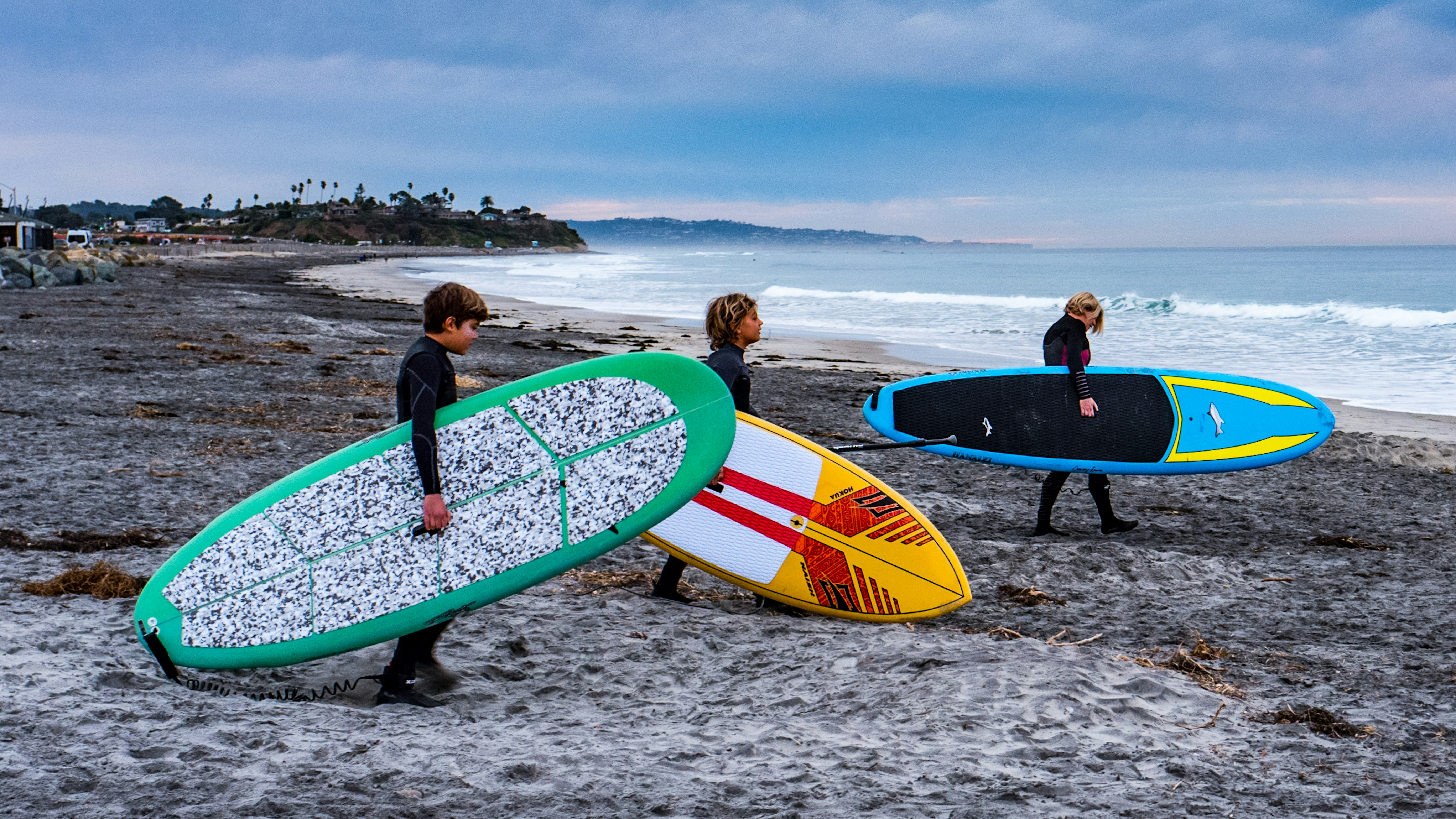 a group of people carrying surfboards on a beach