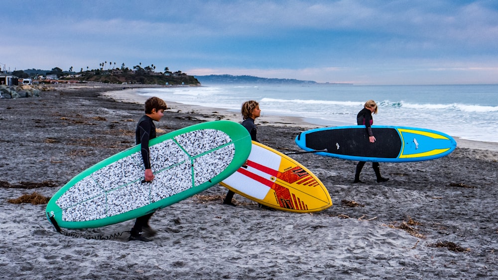 a group of people carrying surfboards on a beach