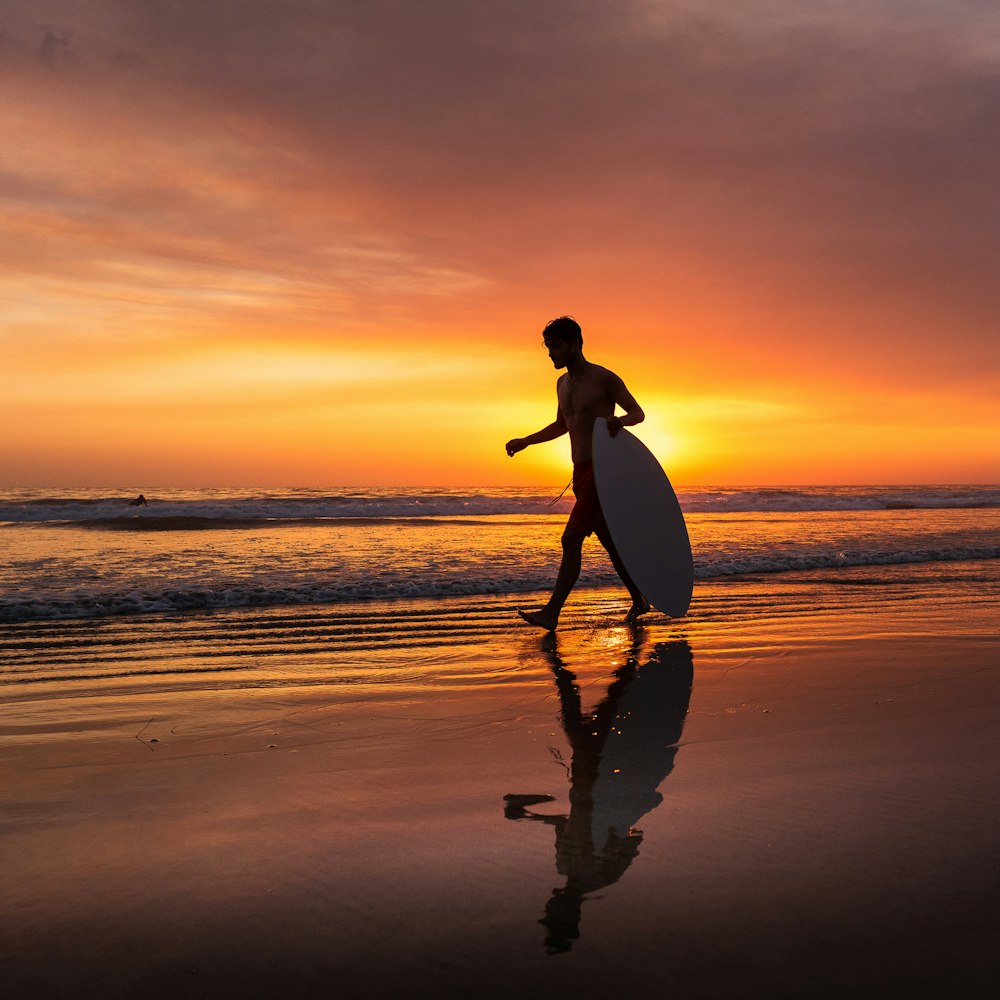 uma pessoa andando em uma praia com uma prancha de surf