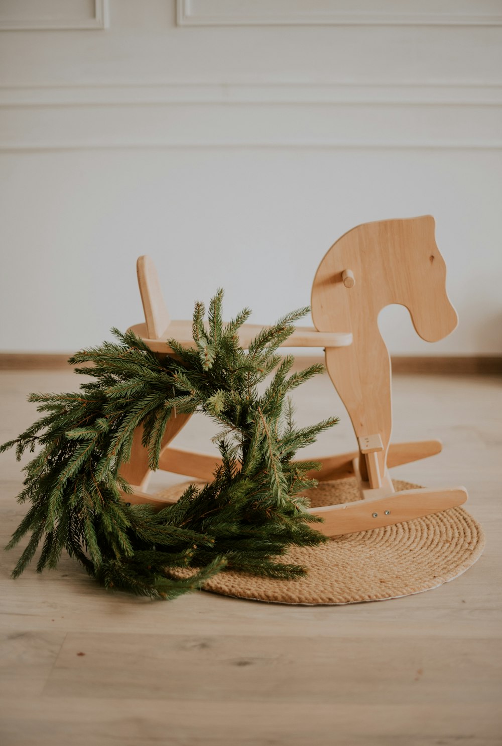 a wooden rocking horse with a wreath on the floor
