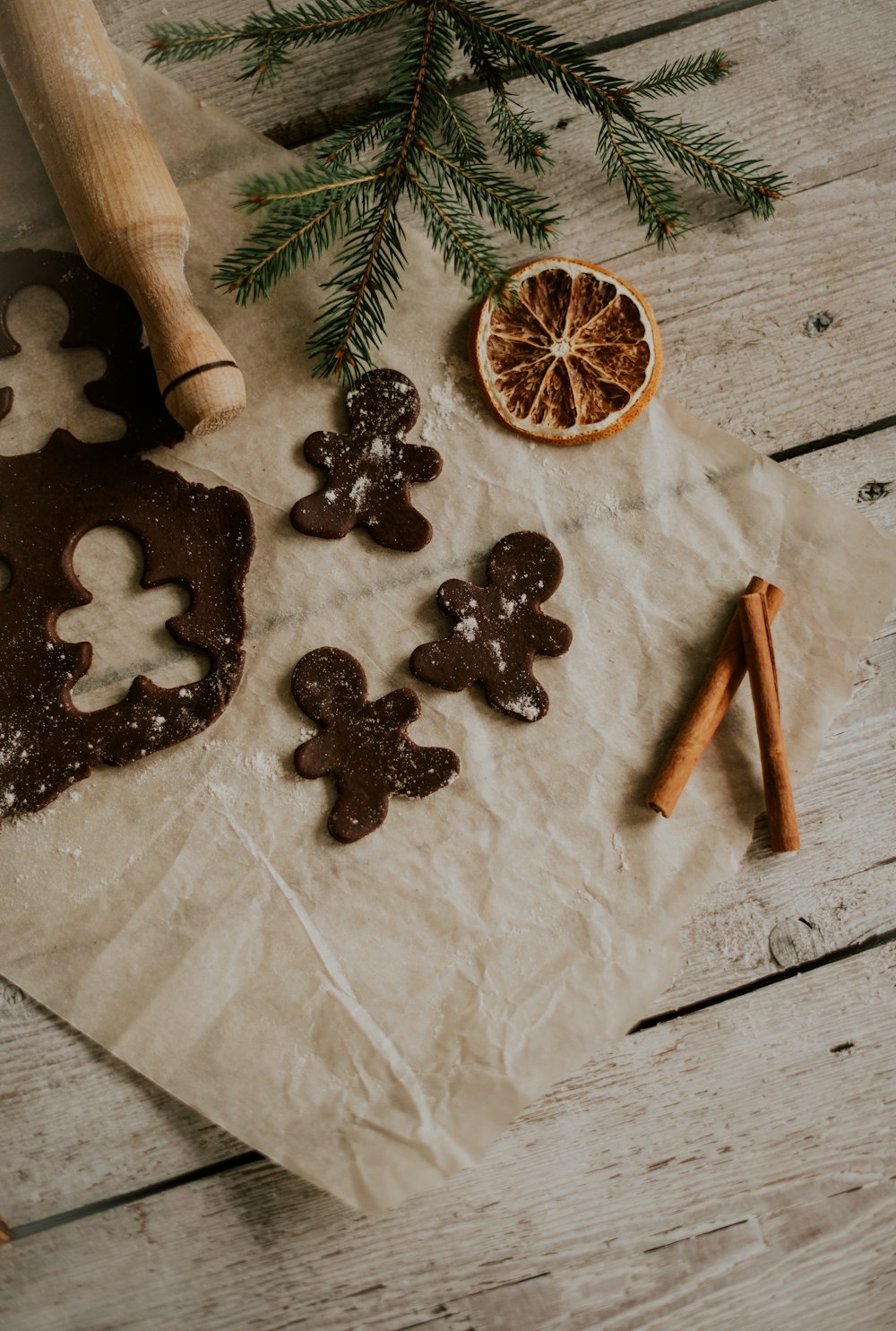 ginger cookies, cinnamon sticks, and a cookie cutter on a piece of parchment paper