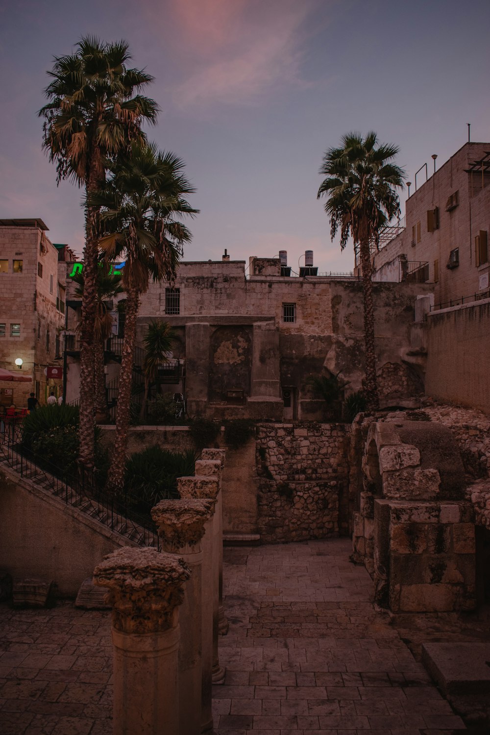 a stone walkway with palm trees in the background