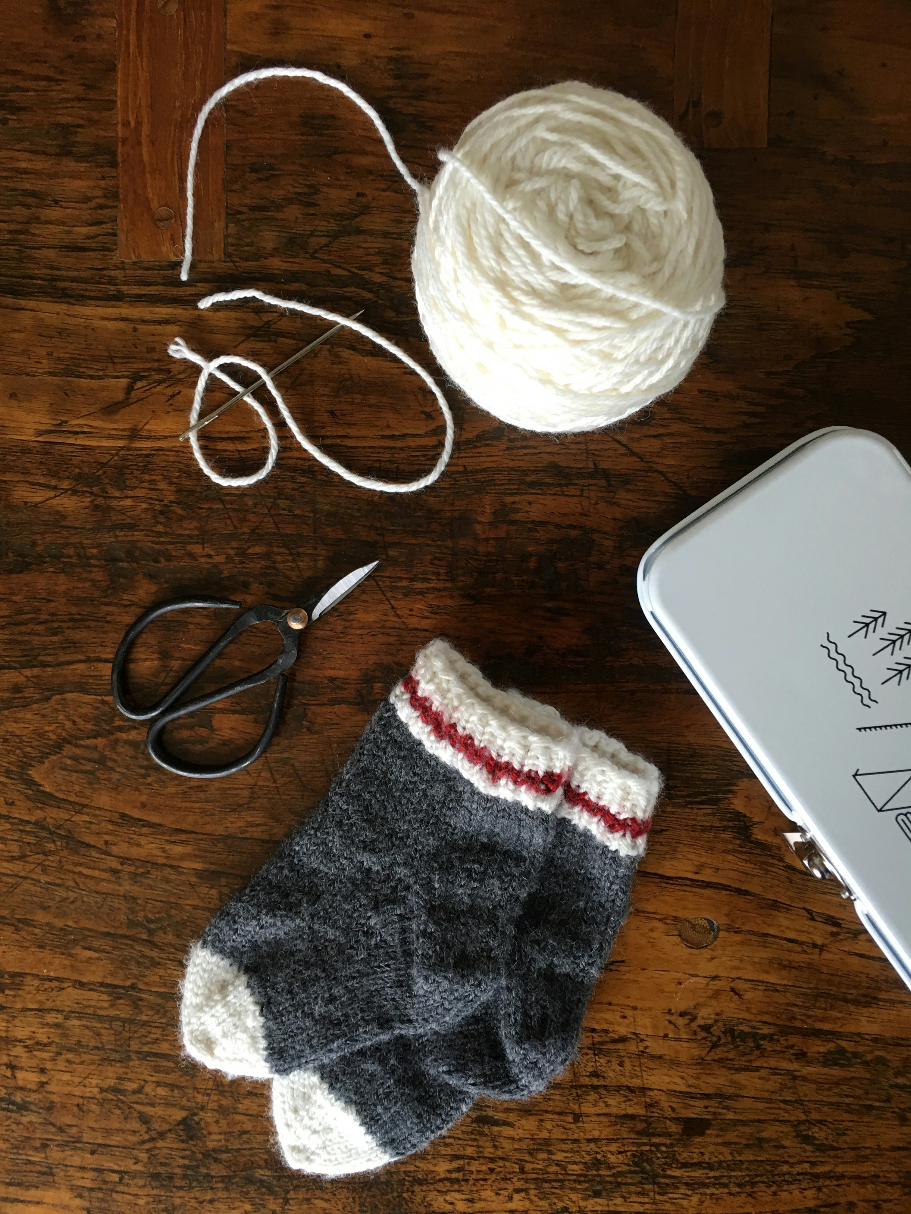 a pair of scissors, a ball of yarn, and a pair of mitts