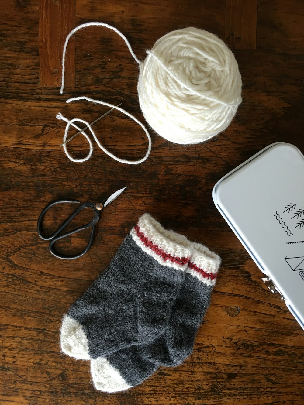 a pair of scissors, a ball of yarn, and a pair of mitts