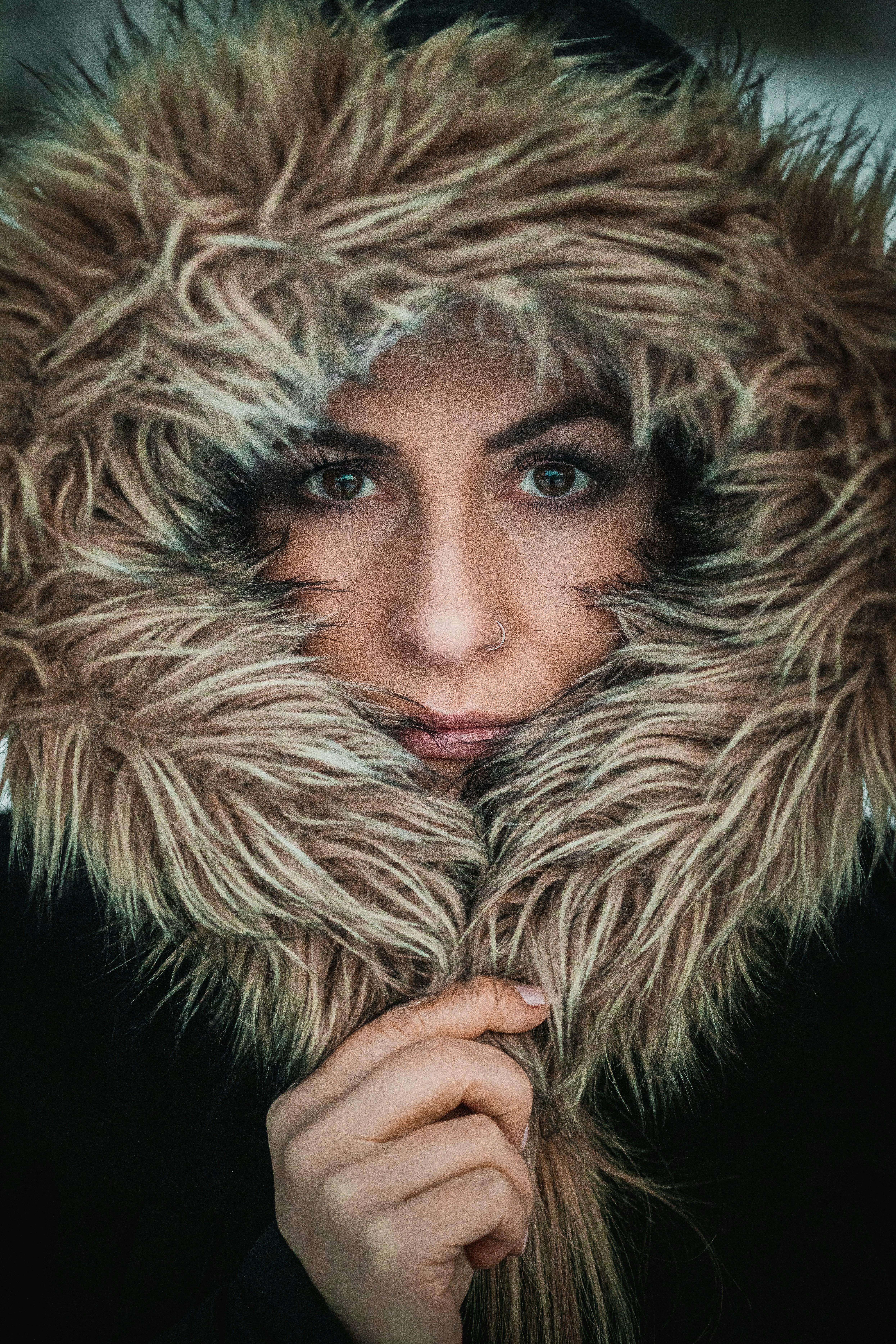a woman wearing a fur coat with a hood over her face