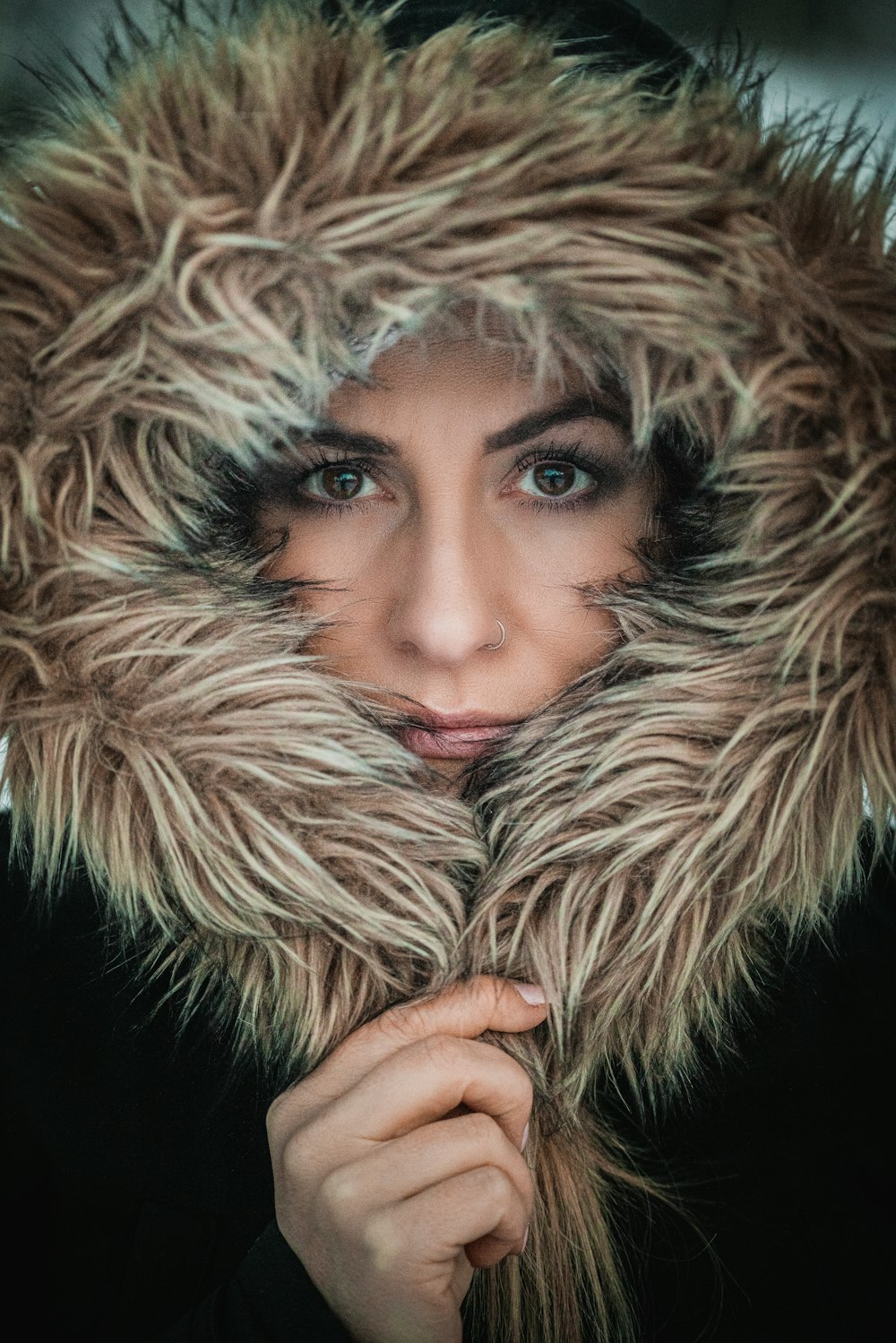 a woman wearing a fur coat with a hood over her face