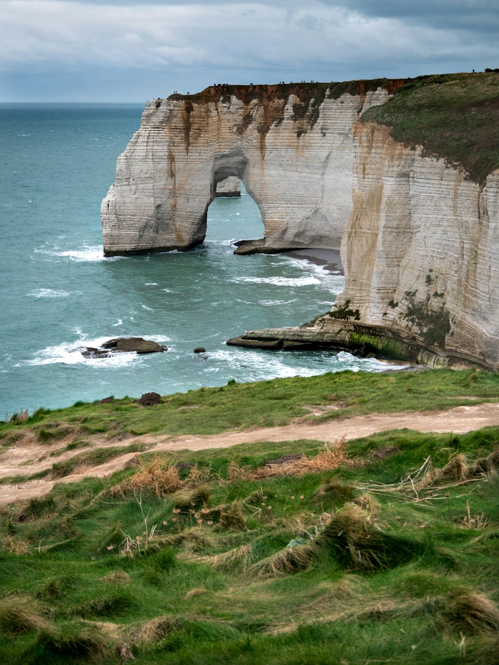 a view of the ocean with a large rock arch in the middle