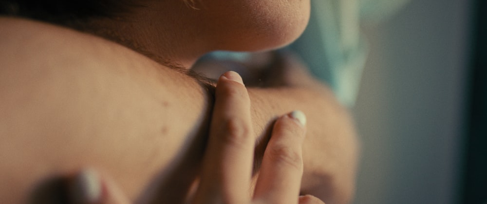 a close up of a woman's shoulder with her hands on her chest
