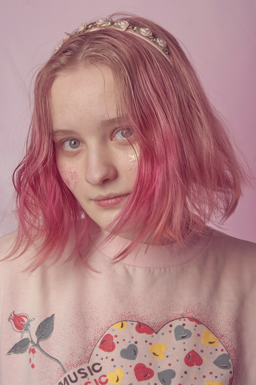 Una ragazza con i capelli rosa che indossa una maglietta con cuori su di esso