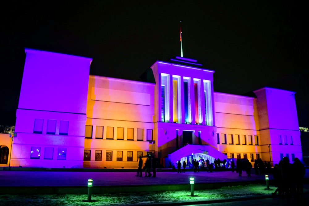 Un edificio iluminado con luces púrpuras por la noche