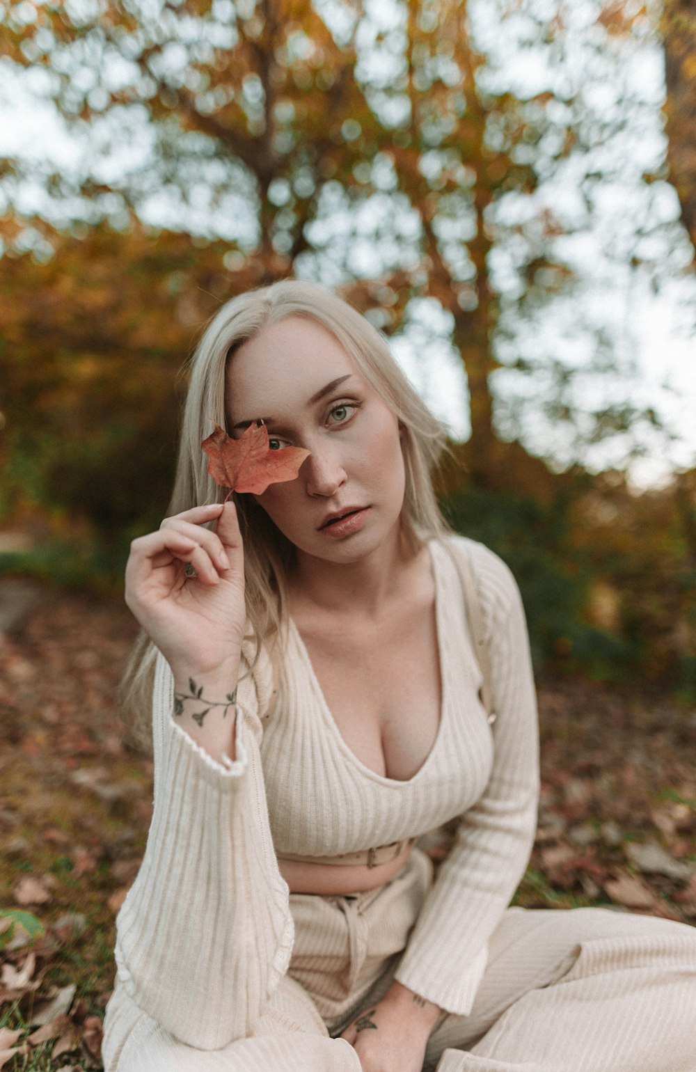 a woman sitting on the ground holding a leaf