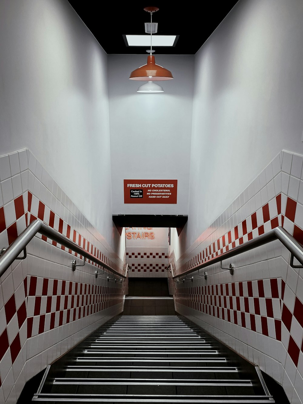 a long set of stairs leading up to a red and white tiled wall