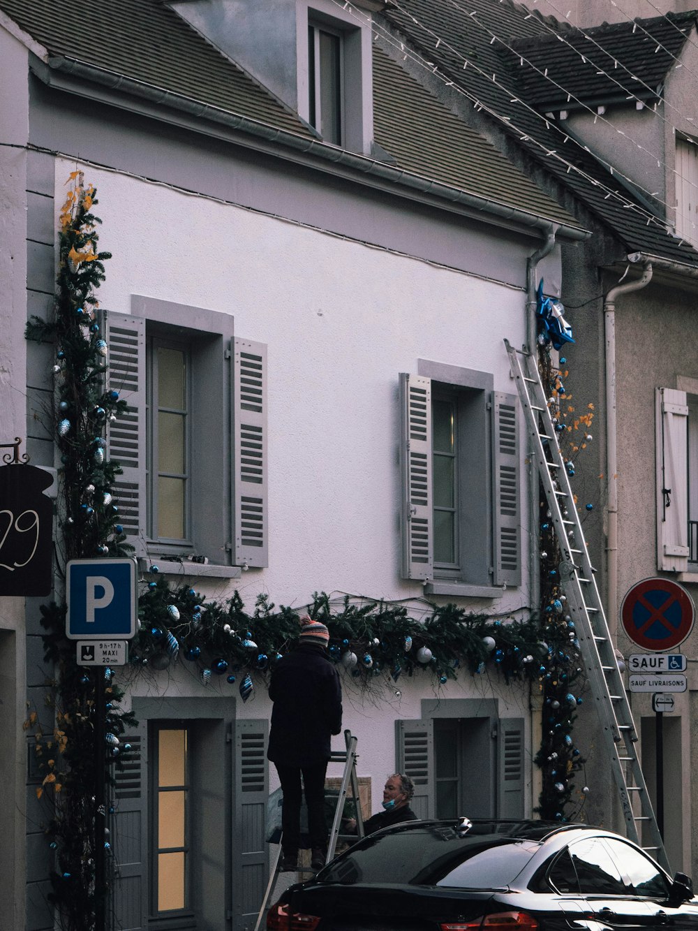 a man standing on a ladder in front of a building