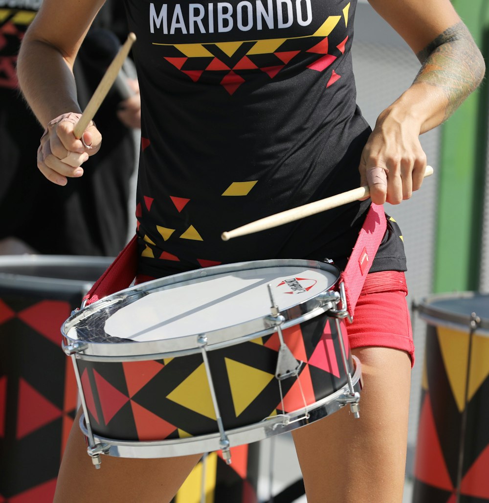 a woman in a black shirt is playing a drum
