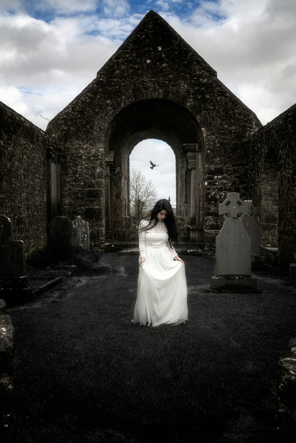 a woman in a white dress standing in a graveyard