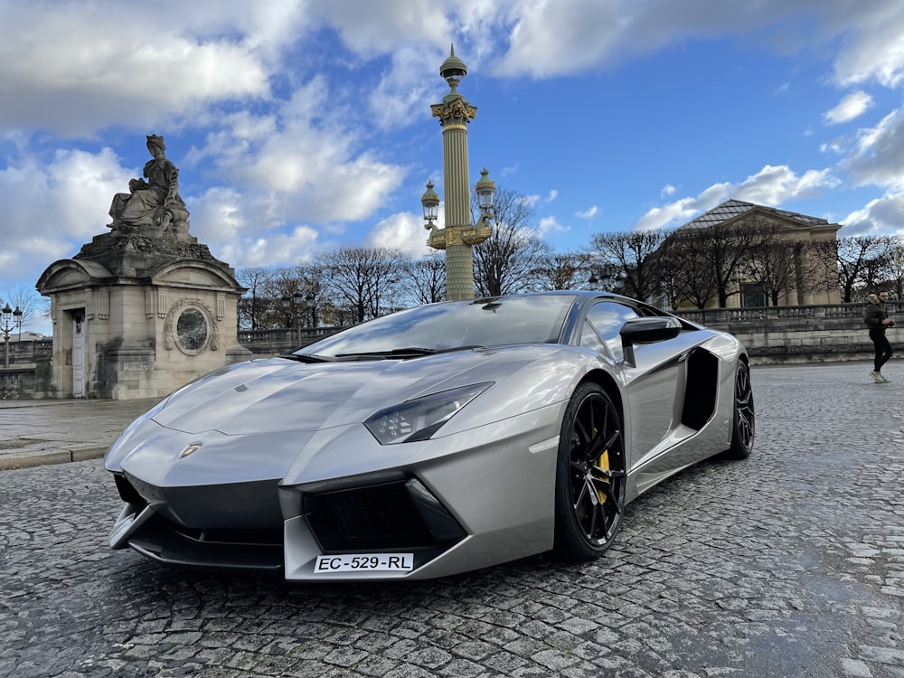 a silver sports car parked on a cobblestone street