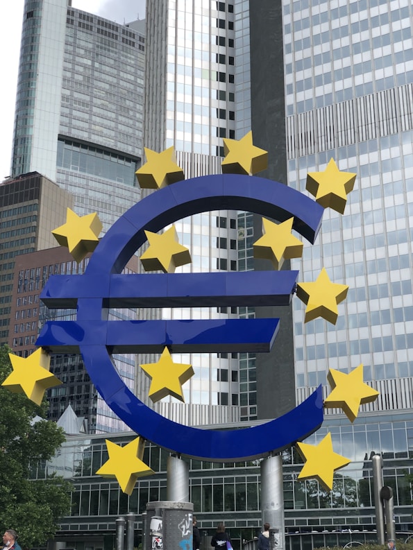 a large blue and yellow euro sign in front of tall buildings