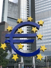 a large blue and yellow euro sign in front of tall buildings