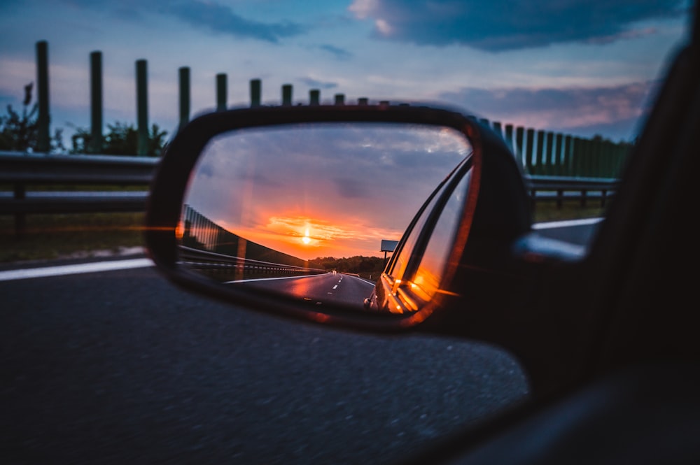 a rear view mirror reflecting a sunset in the side view mirror