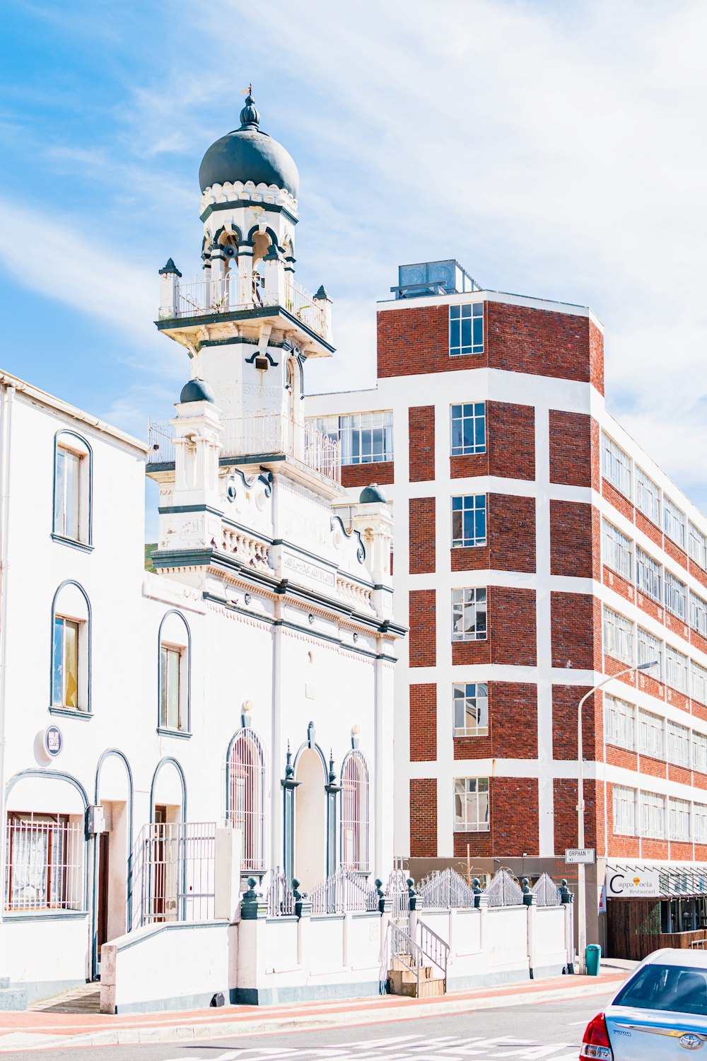 a red car parked in front of a tall white building