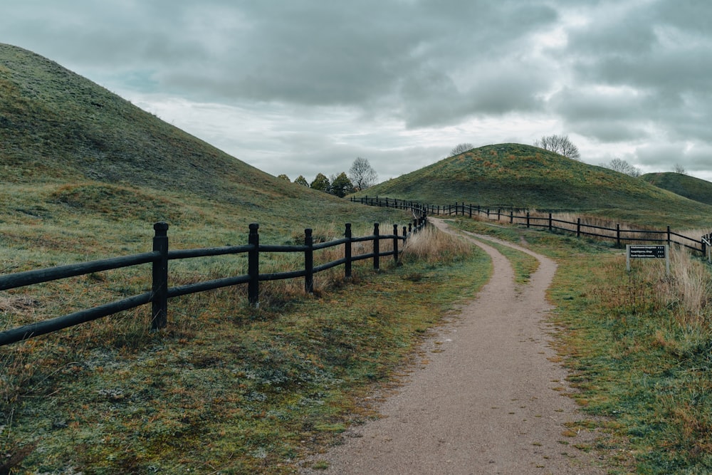 a dirt path leading to a grassy hill