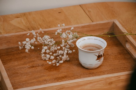 a cup of coffee sitting on top of a wooden tray