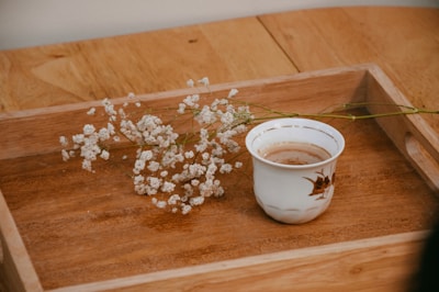a cup of coffee sitting on top of a wooden tray