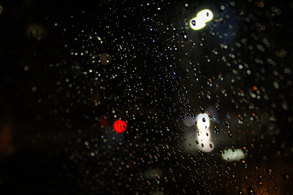 a rain covered window with street lights in the background