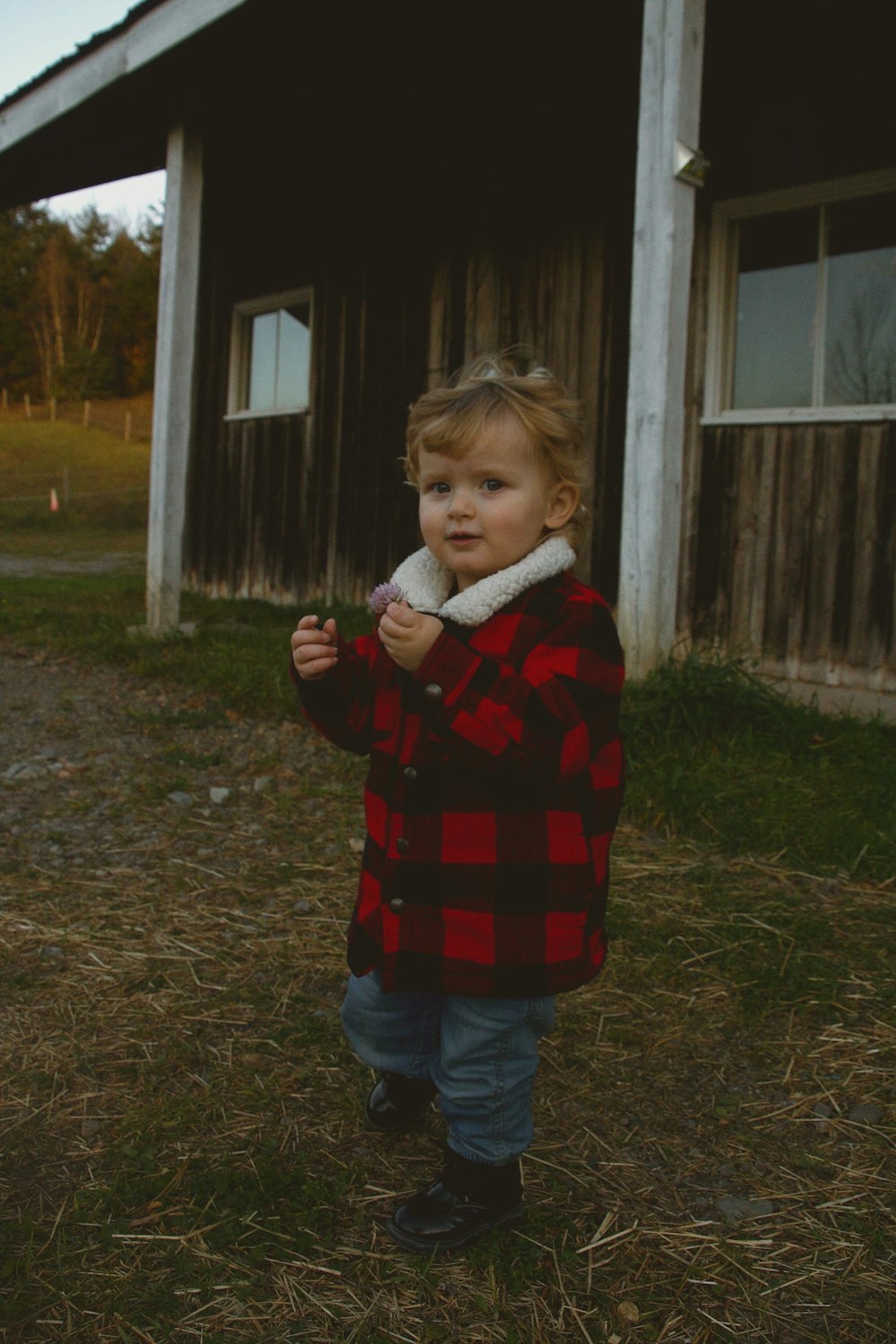 a little girl standing in front of a barn