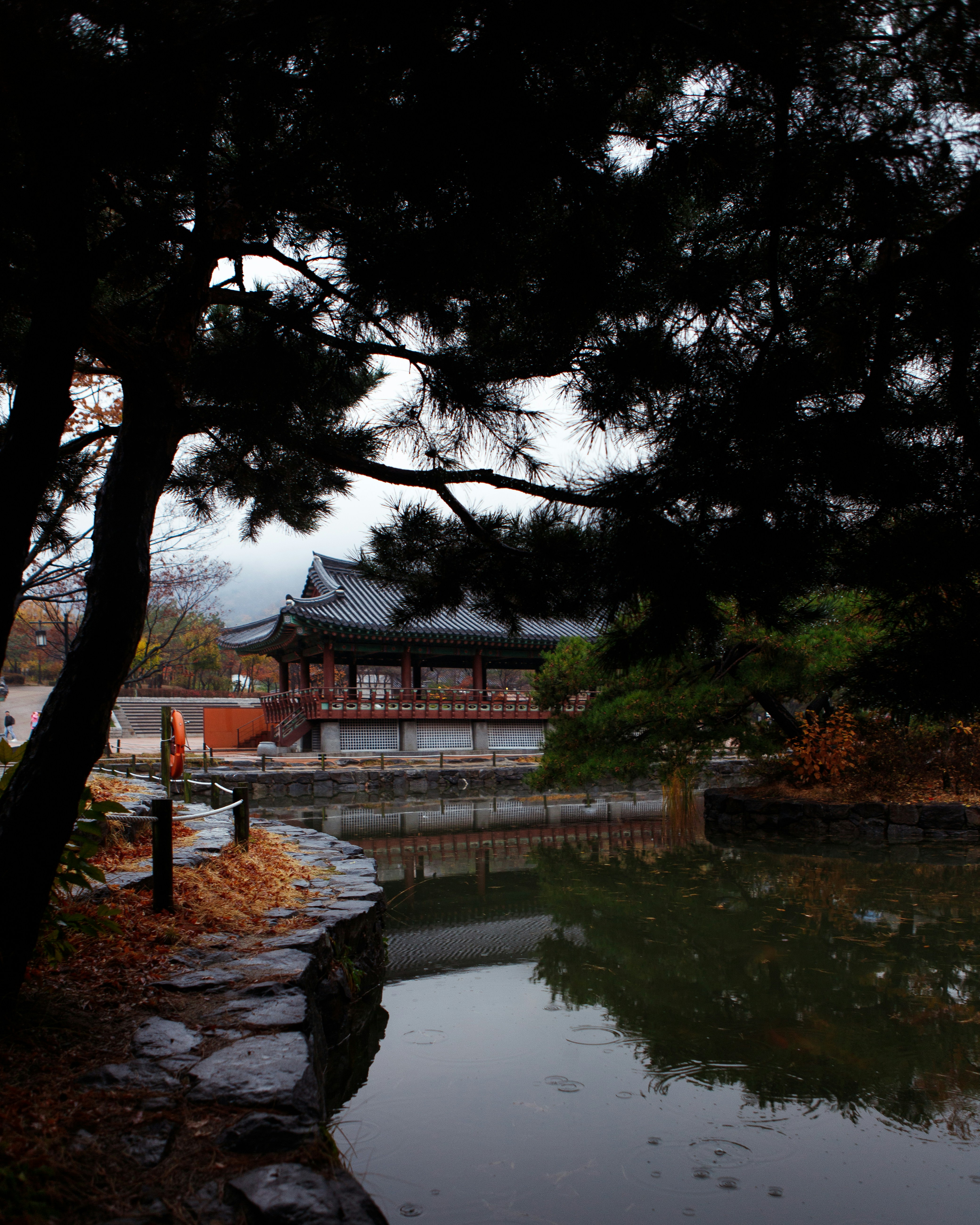 a pond in a park with a pavilion in the background