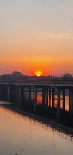 A warm sunset over a peaceful river with a glowing bridge symbolizing connection.